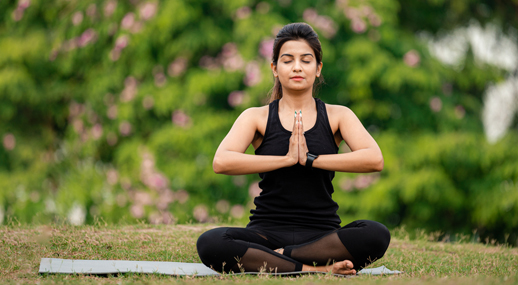 A woman meditating on a mat in a park