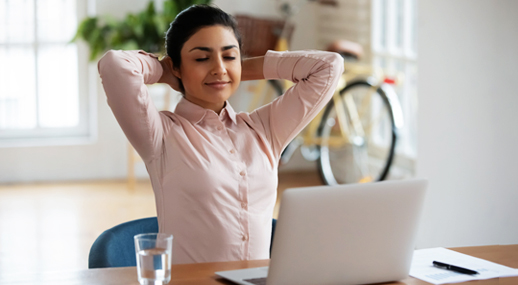A woman leaning back from her desk with her eyes closed