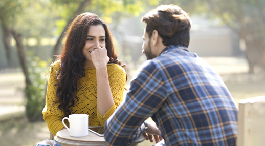 A couple chatting outdoors over a cup of coffee